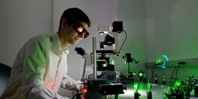 scientist looking through microscope